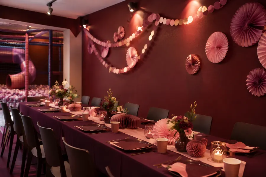 Mesa de cumpleaños decorada con abanicos de papel en tonos rosa cuarzo y vino